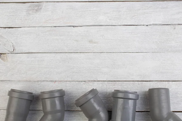 Assorted PVC sewage pipe fittings shot on the wooden background. Top view. Copy space for text