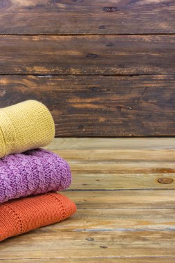 Örgü yün kazaklar. Ahşap arka planda örülmüş yaz kıyafetleri, kazaklar, örgü giysileri, metin için yer.