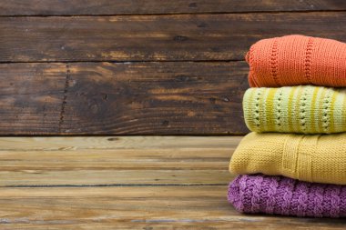 Örgü yün kazaklar. Ahşap arka planda örülmüş yaz kıyafetleri, kazaklar, örgü giysileri, metin için yer.