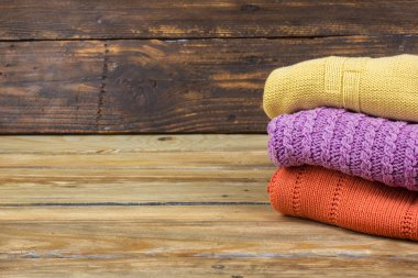 Örgü yün kazaklar. Ahşap arka planda örülmüş yaz kıyafetleri, kazaklar, örgü giysileri, metin için yer.