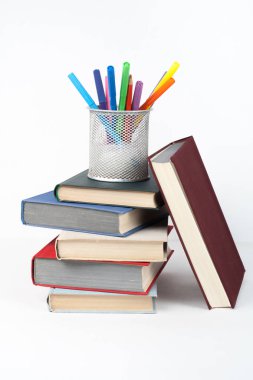 Açık kitap, ahşap masa, beyaz arka plan üzerinde renkli ciltli kitap. Okula dönüş. Kalem, kalem, bardak. Metin için yer kopyalayın. Eğitim iş kavramı