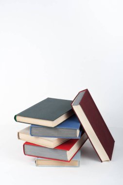 Açık bir kitap, ahşap masa üzerinde ciltli renkli kitaplar, beyaz arka plan. Okula dönelim. Uzayı metin için kopyala. Eğitim sektörü kavramı