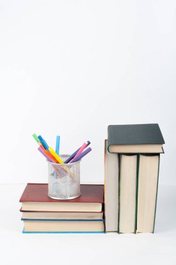 Açık bir kitap, ahşap masa üzerinde ciltli renkli kitaplar, beyaz arka plan. Okula dönelim. Uzayı metin için kopyala. Eğitim sektörü kavramı