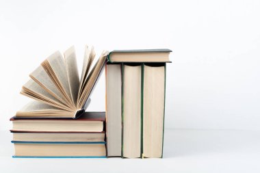 Açık bir kitap, ahşap masa üzerinde ciltli renkli kitaplar, beyaz arka plan. Okula dönelim. Uzayı metin için kopyala. Eğitim sektörü kavramı