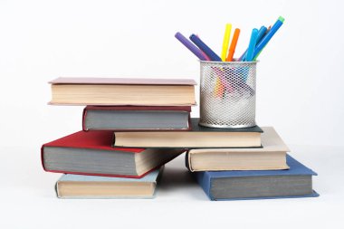 Açık bir kitap, ahşap masa üzerinde ciltli renkli kitaplar, beyaz arka plan. Okula dönelim. Uzayı metin için kopyala. Eğitim sektörü kavramı