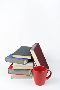 Açık bir kitap, ahşap masa üzerinde ciltli renkli kitaplar, beyaz arka plan. Okula dönelim. Kupa. Uzayı metin için kopyala. Eğitim sektörü kavramı