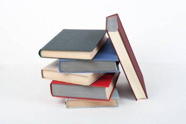 Açık bir kitap, ahşap masa üzerinde ciltli renkli kitaplar, beyaz arka plan. Okula dönelim. Uzayı metin için kopyala. Eğitim sektörü kavramı