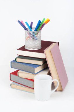 Açık kitap, ahşap masa, beyaz arka plan üzerinde renkli ciltli kitap. Okula dönüş. Kalem, kalem, bardak. Metin için yer kopyalayın. Eğitim iş kavramı