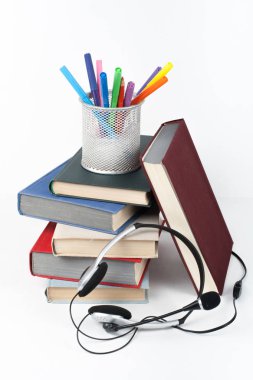 Açık kitap, ahşap masa, beyaz arka plan üzerinde renkli ciltli kitap. Okula dönüş. Kulaklıklar, kalem, kalem, bardak. Metin için yer kopyalayın. Eğitim iş kavramı