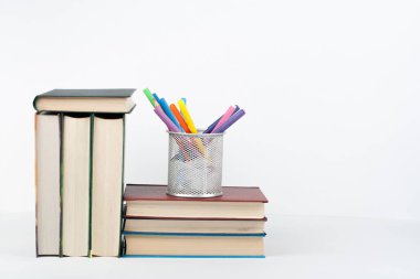 Açık bir kitap, ahşap masa üzerinde ciltli renkli kitaplar, beyaz arka plan. Okula dönelim. Uzayı metin için kopyala. Eğitim sektörü kavramı