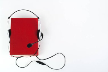 Beyaz arka planda Audiobook. Kulaklıklar mavi kaplı defter, boş kapak, reklam metni için kopyalama alanı. Uzaklık eğitimi, e-öğrenme kavramı