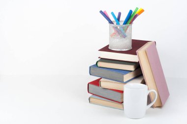 Açık kitap, ahşap masa, beyaz arka plan üzerinde renkli ciltli kitap. Okula dönüş. Kalem, kalem, bardak. Metin için yer kopyalayın. Eğitim iş kavramı