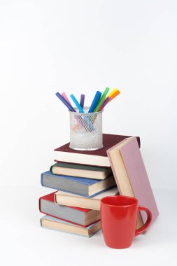 Açık kitap, ahşap masa, beyaz arka plan üzerinde renkli ciltli kitap. Okula dönüş. Kalem, kalem, bardak. Metin için yer kopyalayın. Eğitim iş kavramı