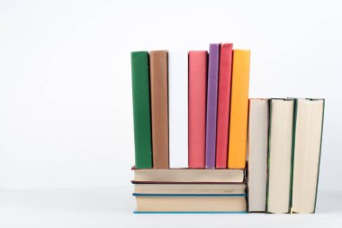 Açık bir kitap, ahşap masa üzerinde ciltli renkli kitaplar, beyaz arka plan. Okula dönelim. Uzayı metin için kopyala. Eğitim sektörü kavramı