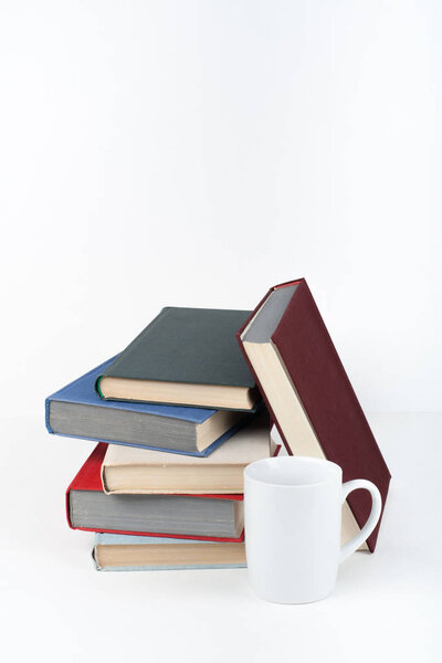 Open book, hardback colorful books on wooden table, white background. Back to school. Cup. Copy space for text. Education business concept