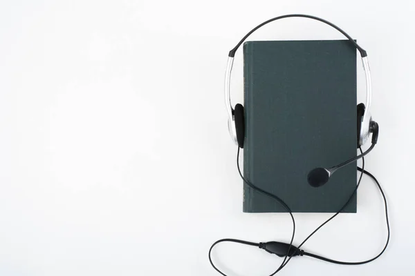 白い背景のオーディオ ブック 緑のハードカバー本 空のカバーに入れてヘッドフォンは 広告テキストのためのスペースをコピーします 遠隔教育 ラーニングの概念 — ストック写真