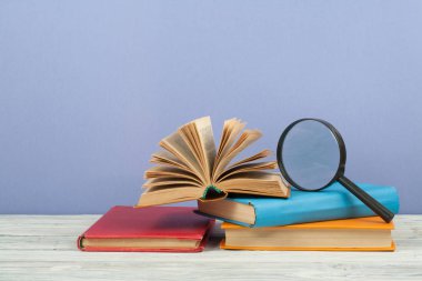 Açık kitap, ahşap masa üzerinde renkli ciltli kitap. Büyüteç'i. Okula dönüş. Metin için yer kopyalayın. Eğitim iş kavramı