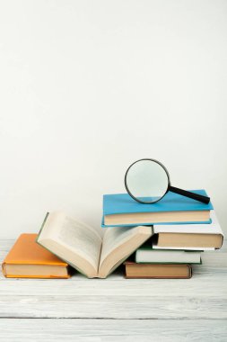 Açık kitap, ahşap masa üzerinde renkli ciltli kitap. Büyüteç'i. Okula dönüş. Metin için yer kopyalayın. Eğitim iş kavramı