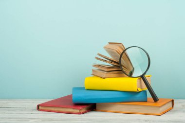 Açık kitap, ahşap masa üzerinde renkli ciltli kitap. Büyüteç'i. Okula dönüş. Metin için yer kopyalayın. Eğitim iş kavramı