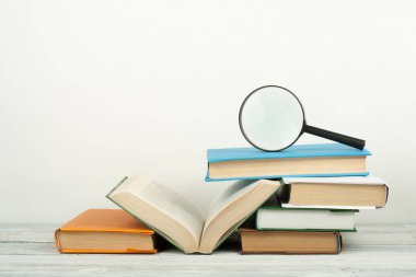 Açık kitap, ahşap masa üzerinde renkli ciltli kitap. Büyüteç'i. Okula dönüş. Metin için yer kopyalayın. Eğitim iş kavramı