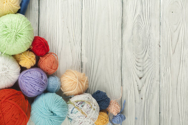 Цветная пряжа на белом фоне. Палочки шерстяной пряжи для вязания. Шары из шерсти разных цветов для ручного вязания на деревянном фоне с копировальным местом для рекламы
