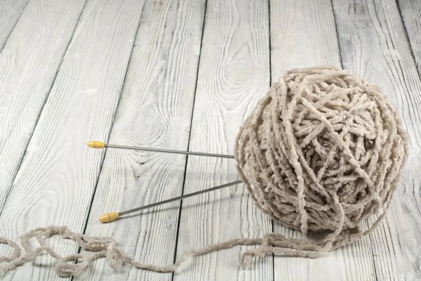 Ball of wool with spokes for handmade knitting on wooden table. Knitting wool and knitting needles