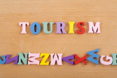 Renkli abc alfabe blok ahşap harflerden oluşan ahşap arka plan üzerinde Turizm kelime, reklam metni için kopya alanı. İngilizce kavramını öğrenme.