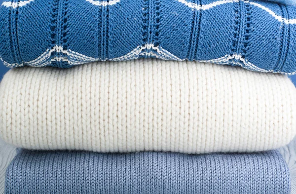 Dzianiny wełniane swetry. Stos dzianiny zimą, jesienne ubrania na niebiesko, drewniane tło, swetry, dzianina, miejsce na tekst. — Zdjęcie stockowe