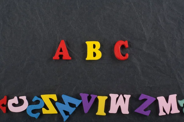 ABC word on black board background composed from colorful abc alphabet block wooden letters, copy space for ad text. Learning english concept.