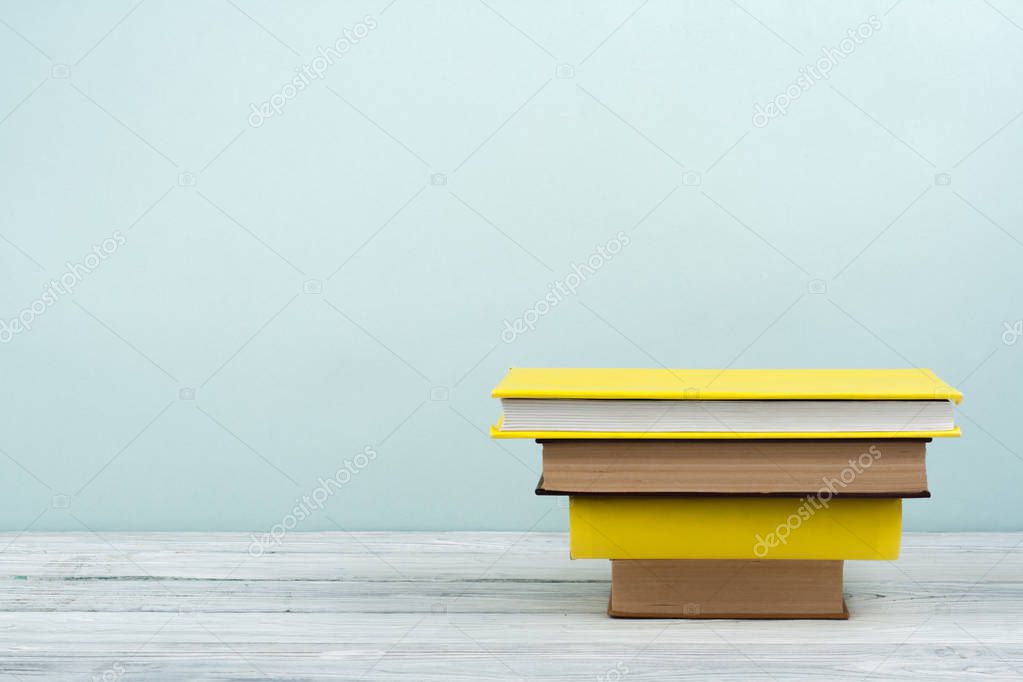 Book stacking. Open book, hardback books on wooden table and blue background. Back to school. Copy space for text.