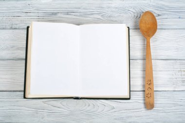 Tarifi ahşap arka plan, kaşık, oklava, damalı masa örtüsü üzerinde boş kitap pişirin. Üstte görüntü