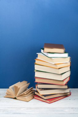 Açık istifleme kitap, ahşap masa ve mavi arka plan üzerinde ciltli renkli kitaplar. Okula geri dön. Metin için alan kopyalayın. Eğitim iş kavramı.