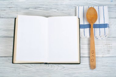 Tarifi ahşap arka plan, kaşık, oklava, damalı masa örtüsü üzerinde boş kitap pişirin. Üstte görüntü