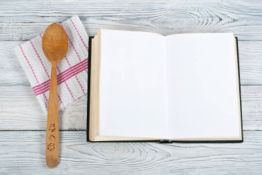 Tarifi ahşap arka plan, kaşık, oklava, damalı masa örtüsü üzerinde boş kitap pişirin. Üstte görüntü