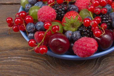 Rustik ahşap masada bir kase çeşitli yaz Taze çilek. Antioksidanlar, detoks diyeti, organik meyveler. Çilek