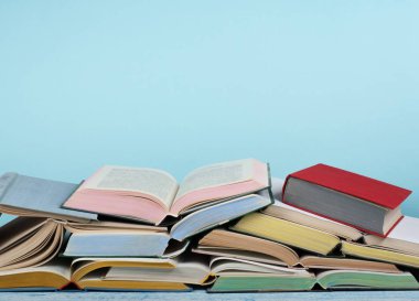 Açık kitap, ahşap masa üzerinde ciltli renkli kitaplar, mavi arka plan. Okula geri dön. Metin için alan kopyalayın. Eğitim iş kavramı.