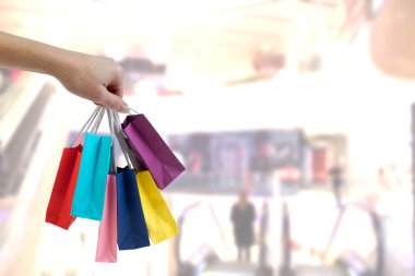 Alışveriş merkezi arka plan üzerinde renkli kağıt torba tutarak kırpma el.