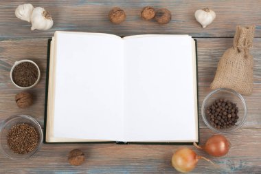 Tarifi ahşap arka plan, kaşık, oklava, damalı masa örtüsü üzerinde boş kitap pişirin. Üstte görüntü