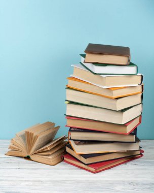 Açık istifleme kitap, ahşap masa ve mavi arka plan üzerinde ciltli renkli kitaplar. Okula geri dön. Metin için alan kopyalayın. Eğitim iş kavramı.