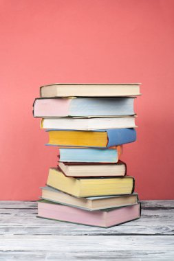 Açık kitap, ahşap masa üzerinde ciltli renkli kitaplar, kırmızı arka plan. Okula geri dön. Metin için alan kopyalayın. Eğitim iş kavramı.