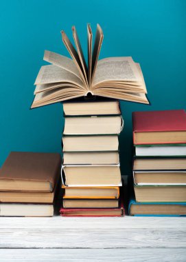 Açık istifleme kitap, ahşap masa ve mavi arka plan üzerinde ciltli renkli kitaplar. Okula geri dön. Metin için alan kopyalayın. Eğitim iş kavramı.