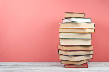 Açık istifleme kitabı, ahşap masa, kırmızı, pembe arka plan üzerinde ciltli renkli kitaplar. Okula geri dön. Metin için alan kopyalayın. Eğitim iş kavramı.