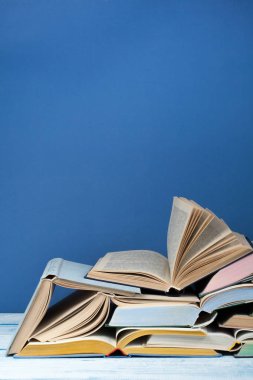 Açık kitap, ahşap masa üzerinde ciltli renkli kitaplar, mavi arka plan. Okula geri dön. Metin için alan kopyalayın. Eğitim iş kavramı.
