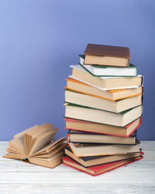 Açık istifleme kitap, ahşap masa ve mavi arka plan üzerinde ciltli renkli kitaplar. Okula geri dön. Metin için alan kopyalayın. Eğitim iş kavramı.