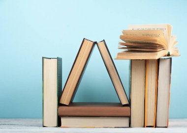 Açık kitap, ahşap masa üzerinde ciltli renkli kitaplar, mavi arka plan. Okula geri dön. Metin için alan kopyalayın. Eğitim iş kavramı.