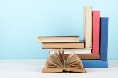 Açık kitap, ahşap masa üzerinde ciltli renkli kitaplar, mavi arka plan. Okula geri dön. Metin için alan kopyalayın. Eğitim iş kavramı.