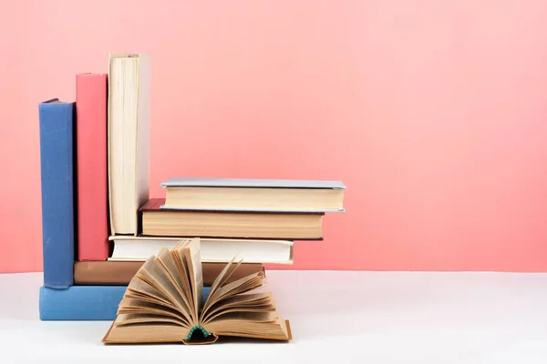 Відкрита книга, різнокольорові книги на дерев'яному столі, червоний, рожевий фон. Повернутися до школи. Копіювати простір для тексту. Освіта бізнес концепція . — стокове фото