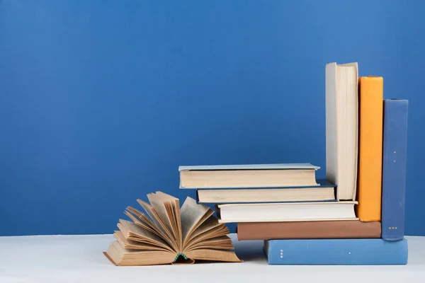 Libro abierto, libros de colores sobre mesa de madera, fondo azul. De vuelta a la escuela. Copia espacio para texto. Concepto de negocio educativo . —  Fotos de Stock