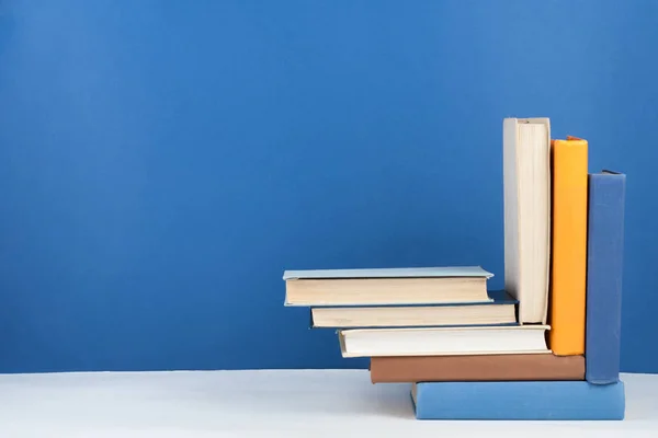 Open book, hardback colorful books on wooden table, blue background. Back to school. Copy space for text. Education business concept. — Stock Photo, Image