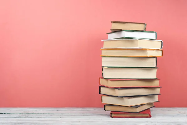 Libro de apilamiento abierto, libros de colores en tapa dura sobre mesa de madera, fondo rojo, rosa. De vuelta a la escuela. Copia espacio para texto. Concepto de negocio educativo . —  Fotos de Stock